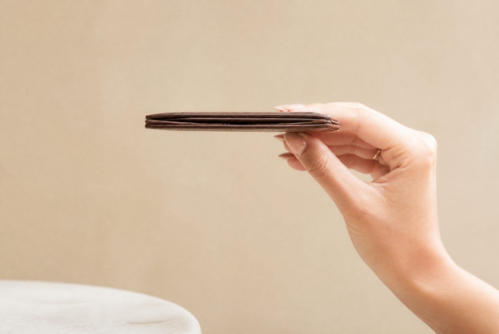 A minimalist card case held in hand showing its slim profile with cards