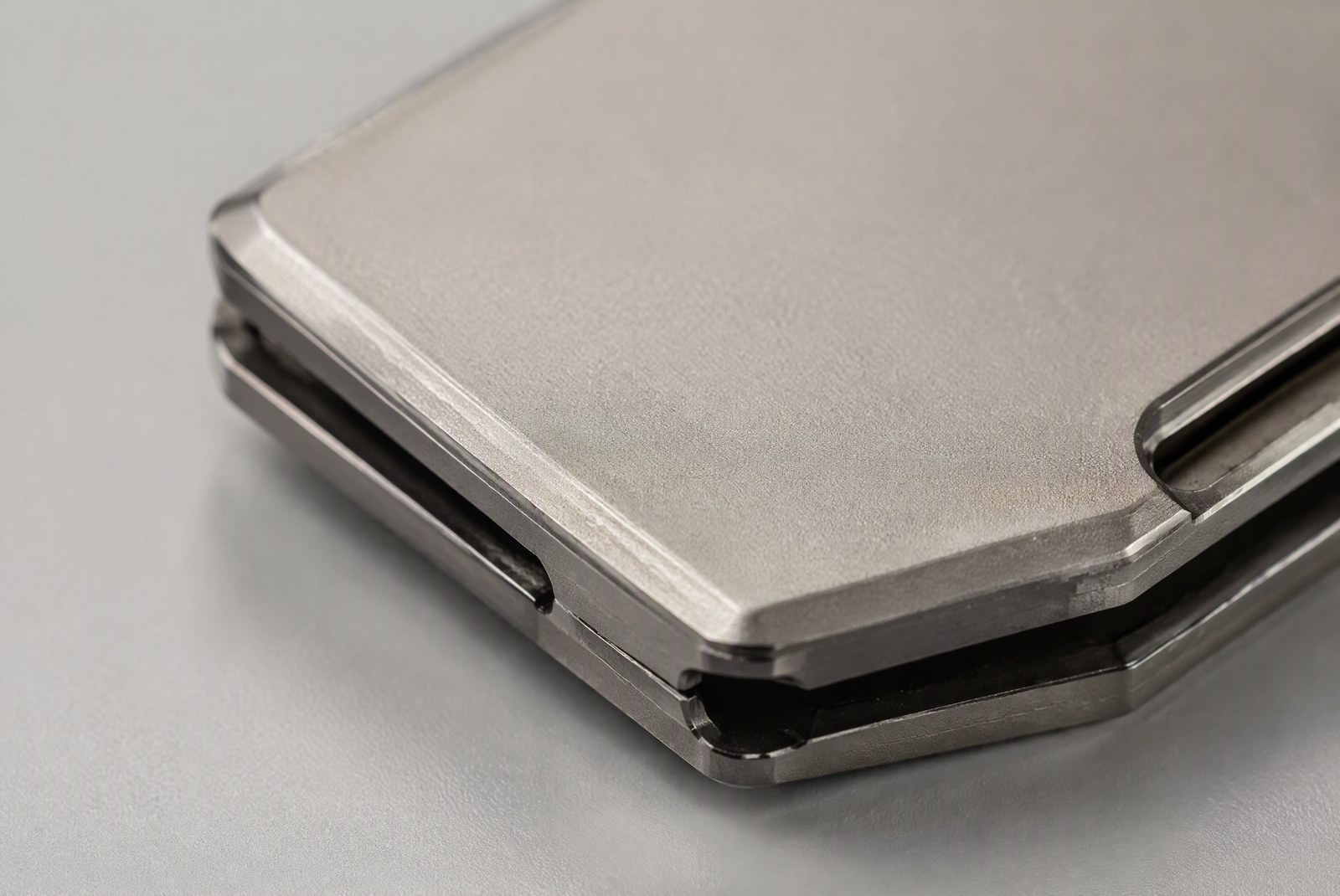feature: extreme macro of a brushed titanium plate showing grain, chamfered edge and engraved markings, material close-up