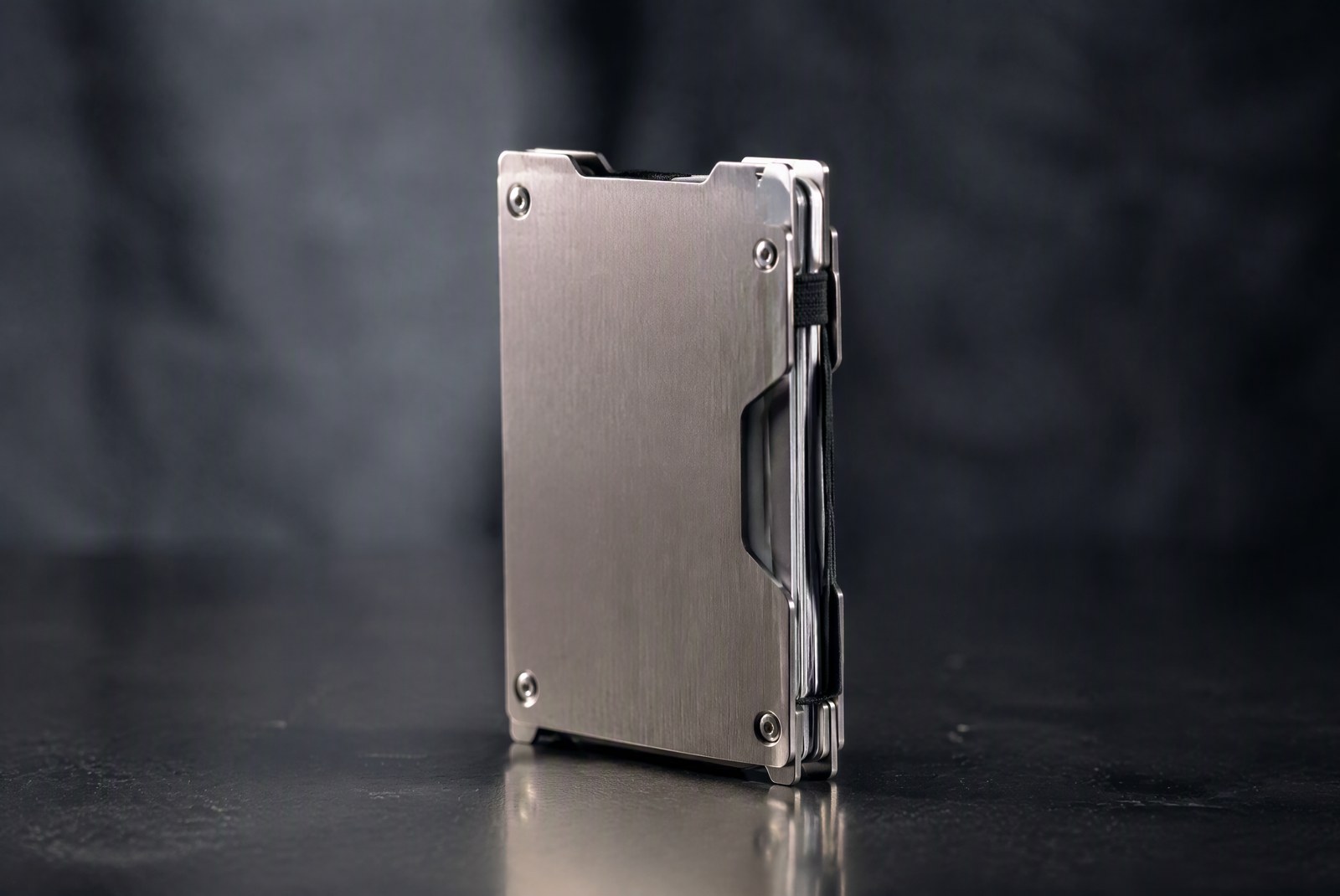 hero: macro studio shot of a titanium two-plate wallet with brushed metal grain visible, product photography