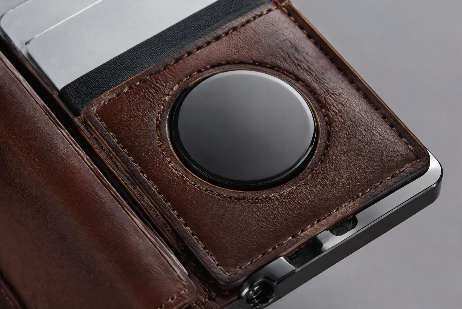 feature: macro studio photography of wallet materials and construction, showing the AirTag slot pocket depth inside aluminum and leather wallets