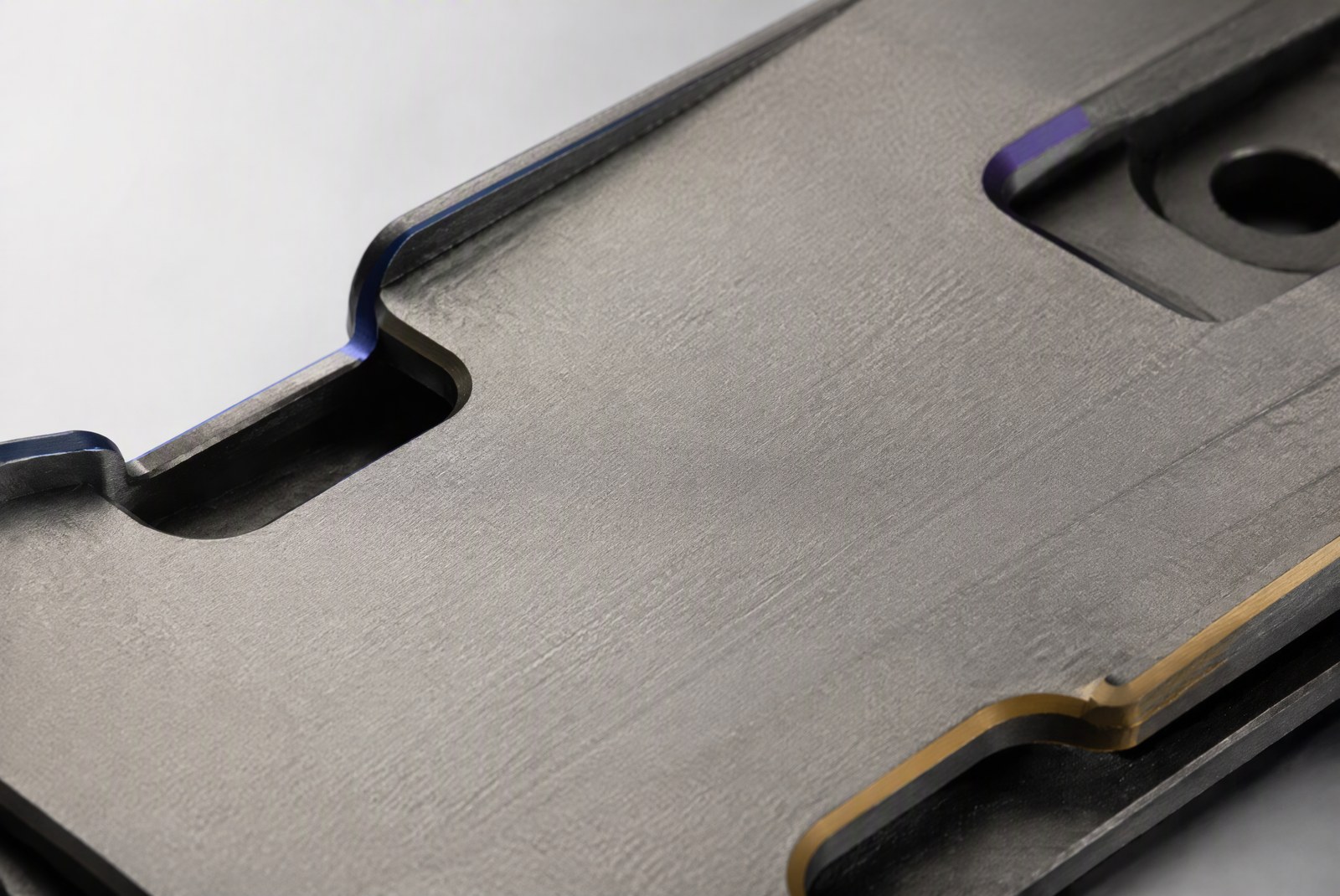 feature: factory photography of a CNC machining center cutting titanium parts with coolant spray, a machinist monitoring the process in the background